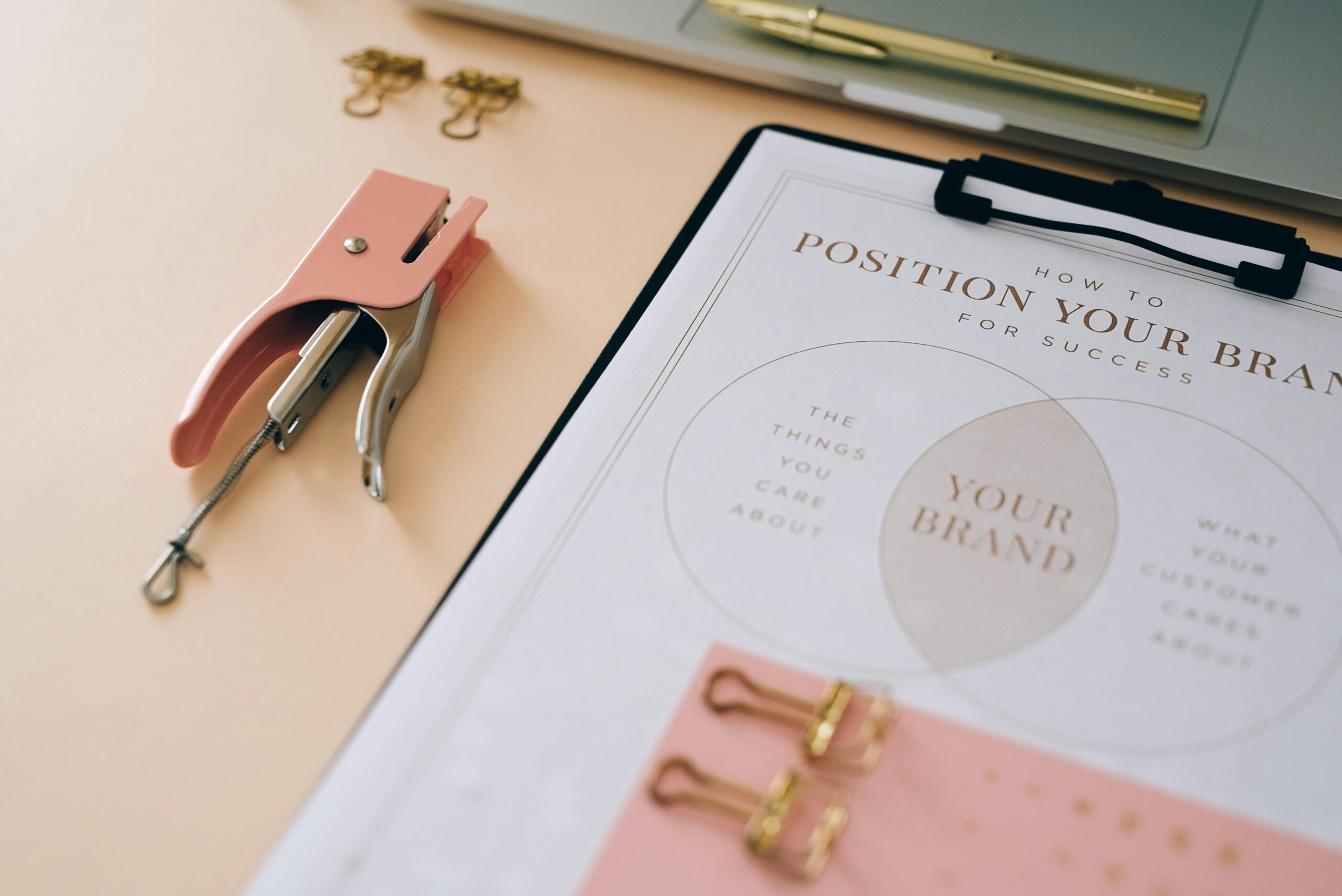 Pink stapler and branding document on a desk showcasing stylish office setup.